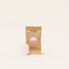 A small, pink Bathroom Cleaner Tablet Refill lies in front of a brown packet labeled Blueland Bathroom Cleaner, featuring a refreshing Eucalyptus Mint scent. This eco-friendly product uses plant-based ingredients and weighs 0.27 oz (7.7 g), ideal for bathroom refills.